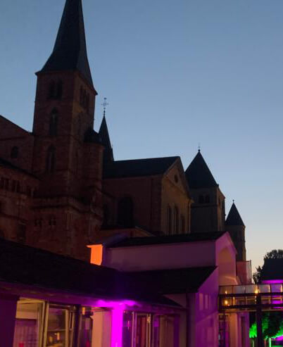 Das Museum am Dom Trier während der Trierer Museumsnacht mit stimmungsvoller violetter Beleuchtung und Blick auf den Dom im Hintergrund.